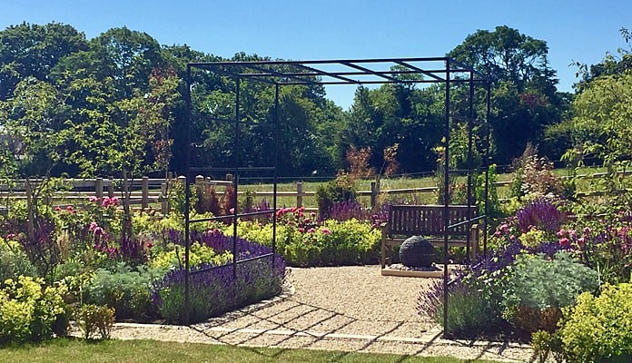 Daisy Barn Garden Square Pergola with seating area and water feature behind