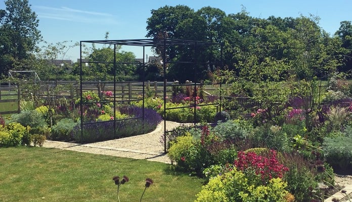 Daisy Barn Garden Square Pergola with seating area and water feature behind